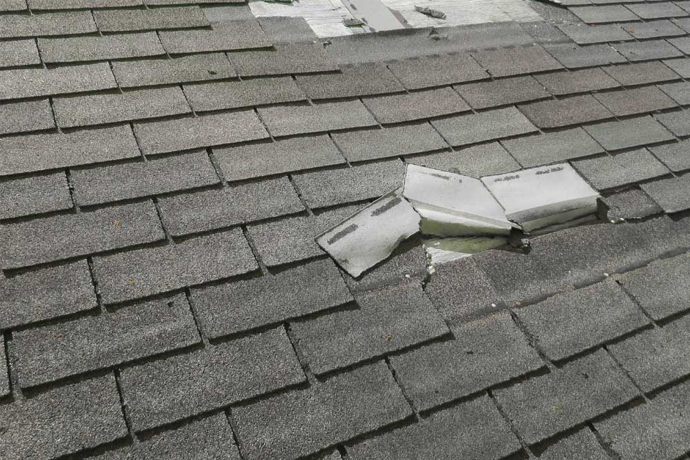 Korrect Roofing inspection of a damaged asphalt shingle roof with broken and lifted shingles exposing underlayment.