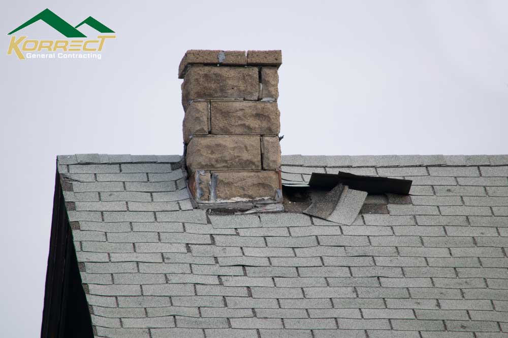 Damaged shingles near chimney showing roof wear that may require repair or replacement in DFW homes.