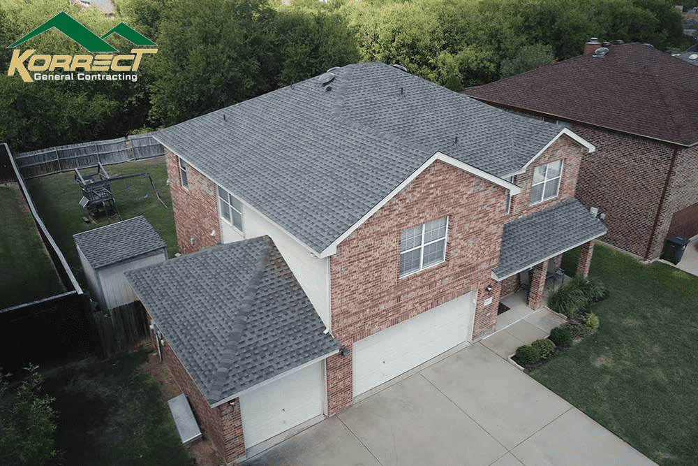 Aerial view of a DFW brick home with a new gray shingle roof installed by Korrect General Contracting.