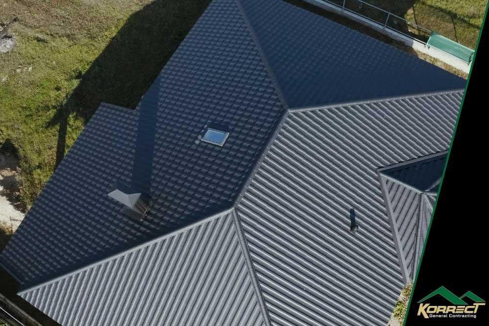 Aerial view of a home with a newly installed dark metal roof, taken in daylight with Korrect General Contracting